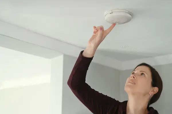 Young Adult Woman Female Age testing smoke alarm.