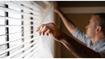 Man adjusting blinds.