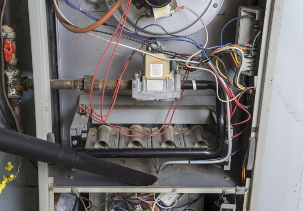 Technician using vacuum to clean dust from inside of furnace