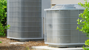 Pair of AC condenser units on concrete pads.