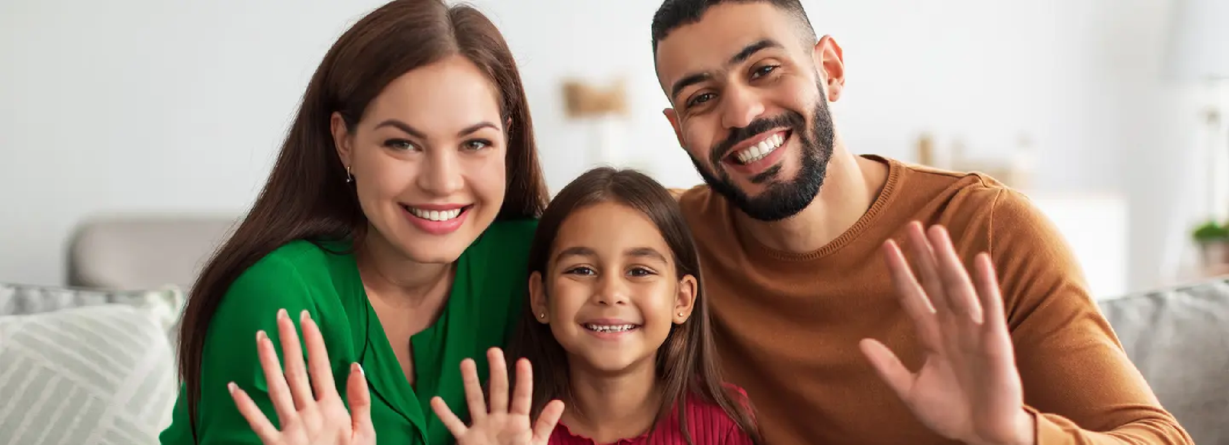 A happy family of three smiling and waving at camera. 