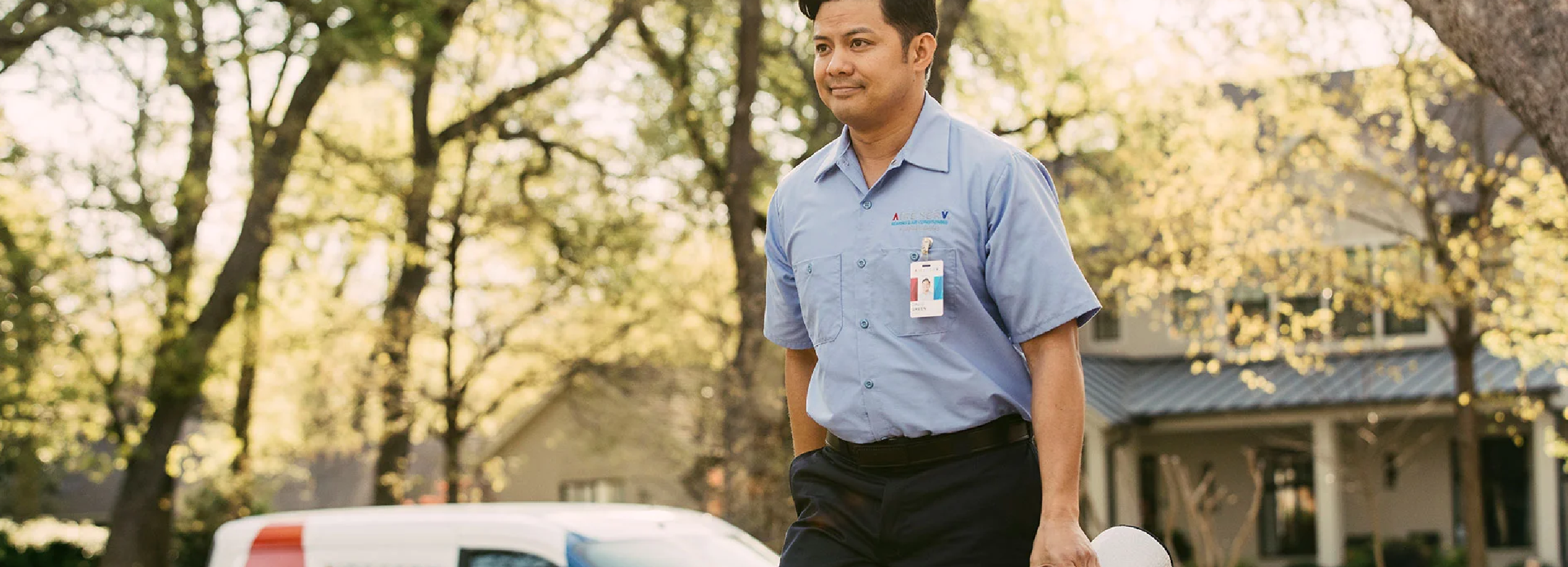 Smiling male Aire Serv technician in branded blue collared shirt arriving for residential service call.