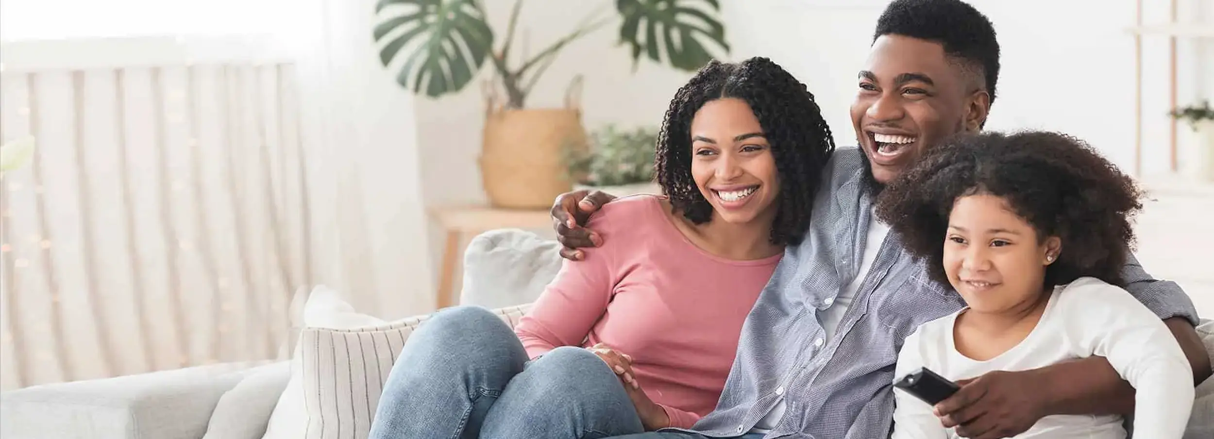 Smiling African American family sitting on couch together.