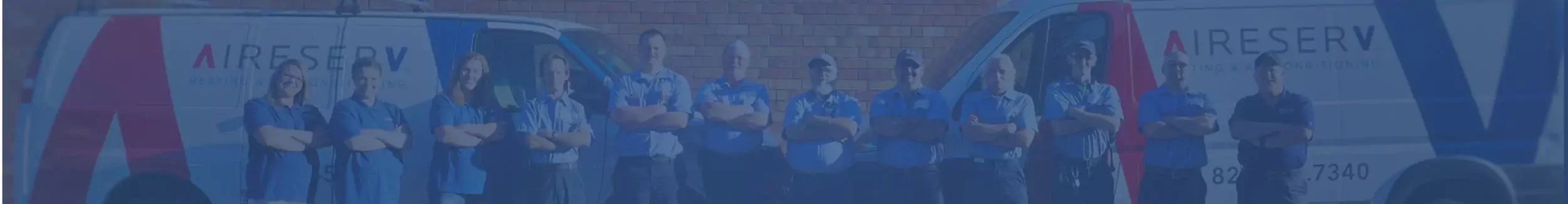 Row of Aire Serv technicians standing with arms crossed between pair of branded vans.