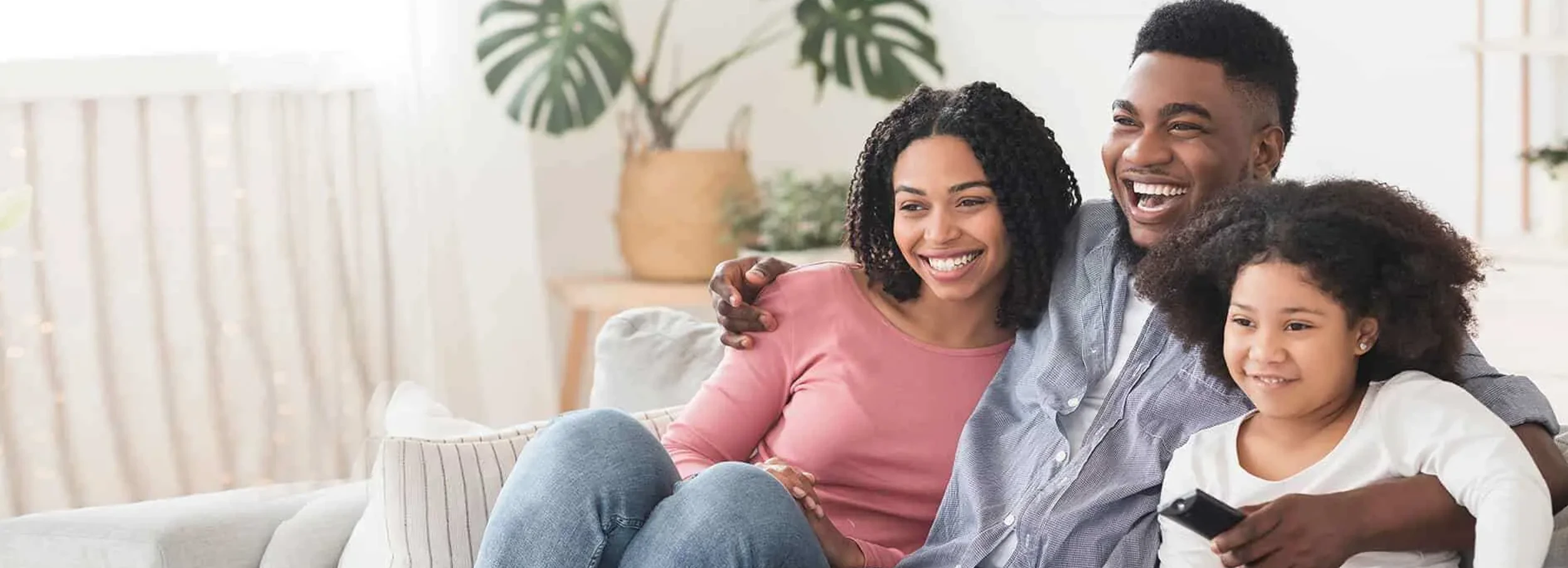 Happy African American family sitting on couch watching television.